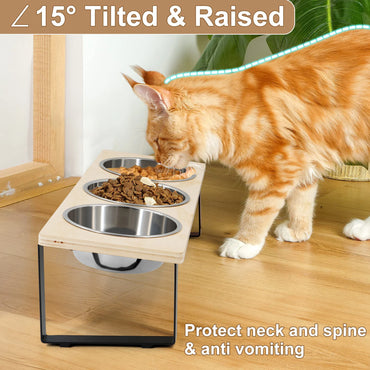 Cat using a raised and tilted pet feeding station with three bowls on a wooden floor.
